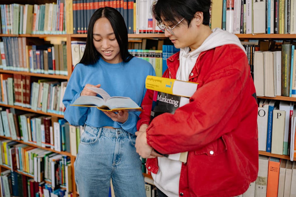 Two students engaged in collaborative study at a university library, sharing books and ideas.