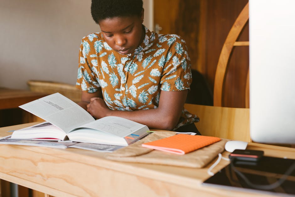 A young woman studies a book at her desk in a warm, indoor setting, illustrating a calm study environment.